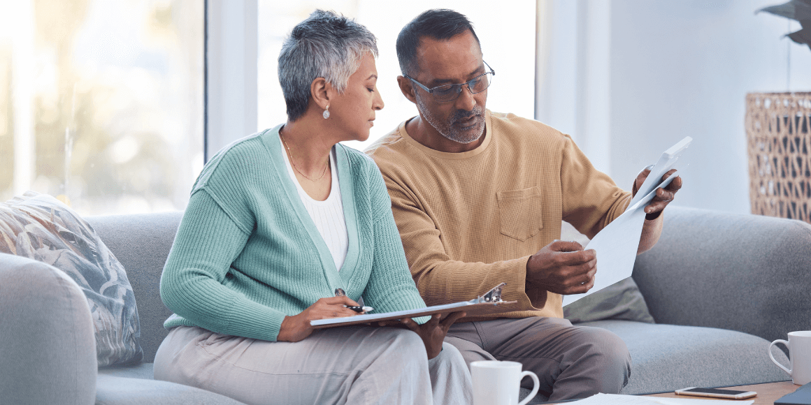Older couple sitting on the couch reviewing their bank statements