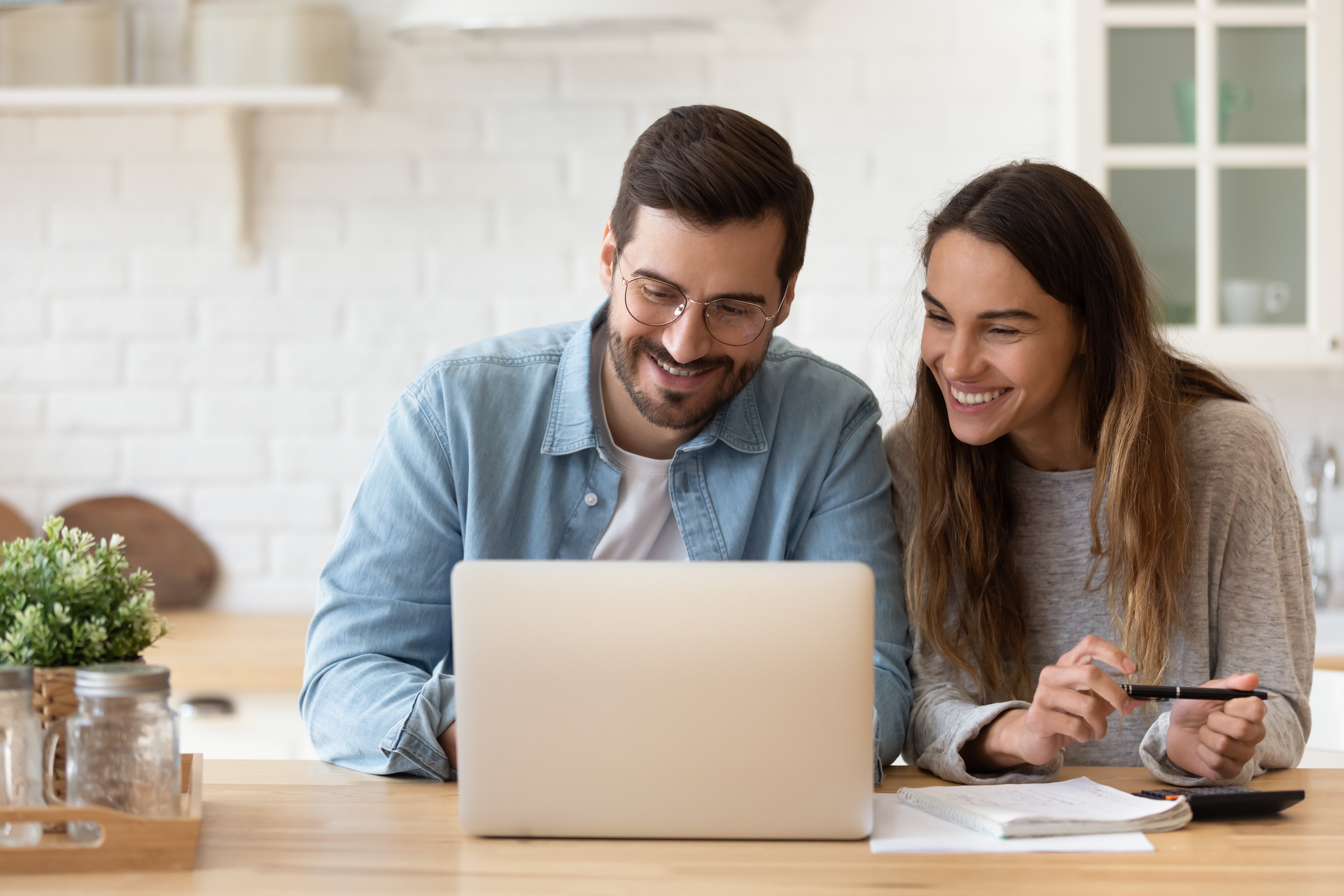 A couple sitting at a kitchen table with a laptop and paperwork, strategizing ways to prepare for retirement