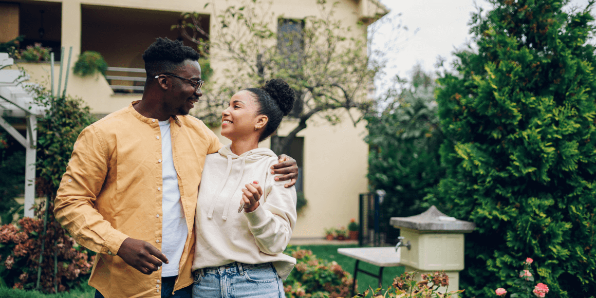 Happy couple standing outside of their new home