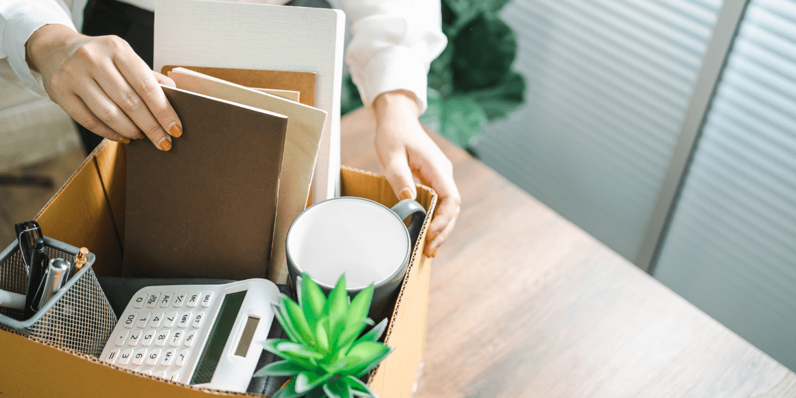 A woman packing office supplies from her desk into a box