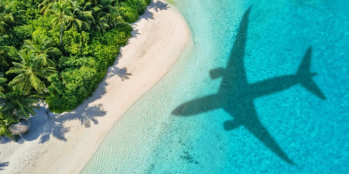 Shadow of an airplane over the beach of a tropical island