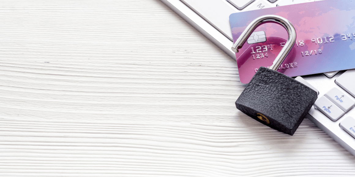 An open lock laying on top of a credit card and a keyboard