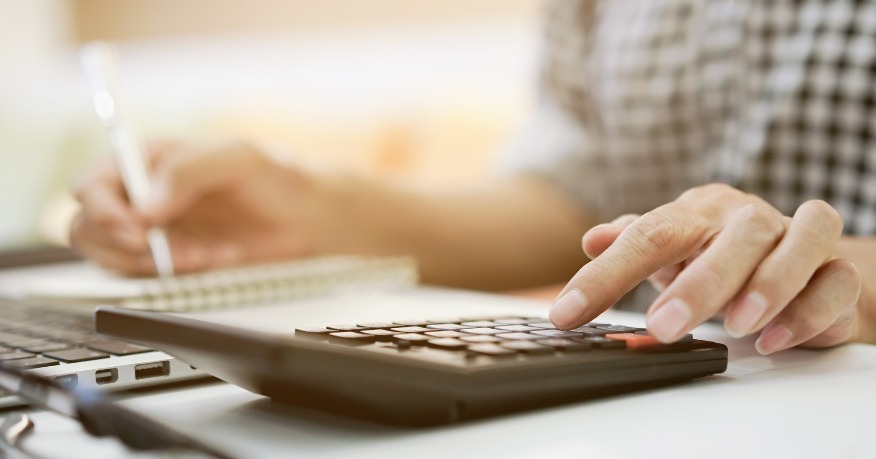 A person sitting at their desk calculating their expenses