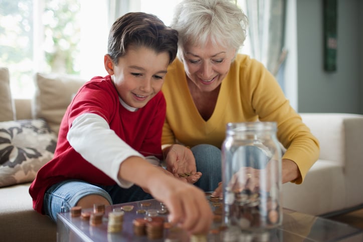 Grandmother teaching her grandson about finances by counting coins in the living room