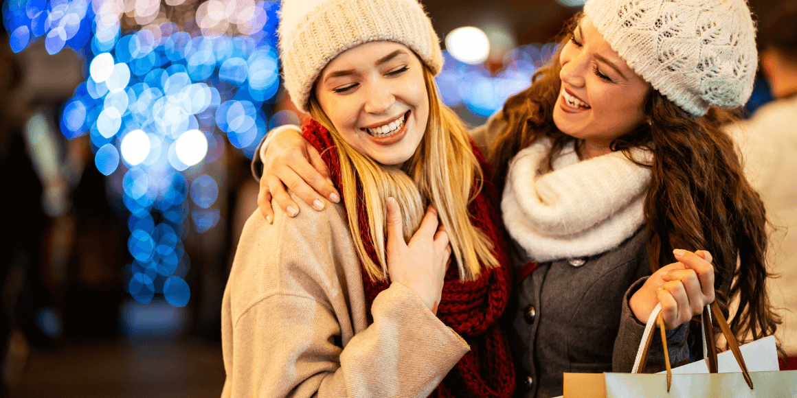 two friends laughing while doing their holiday shopping
