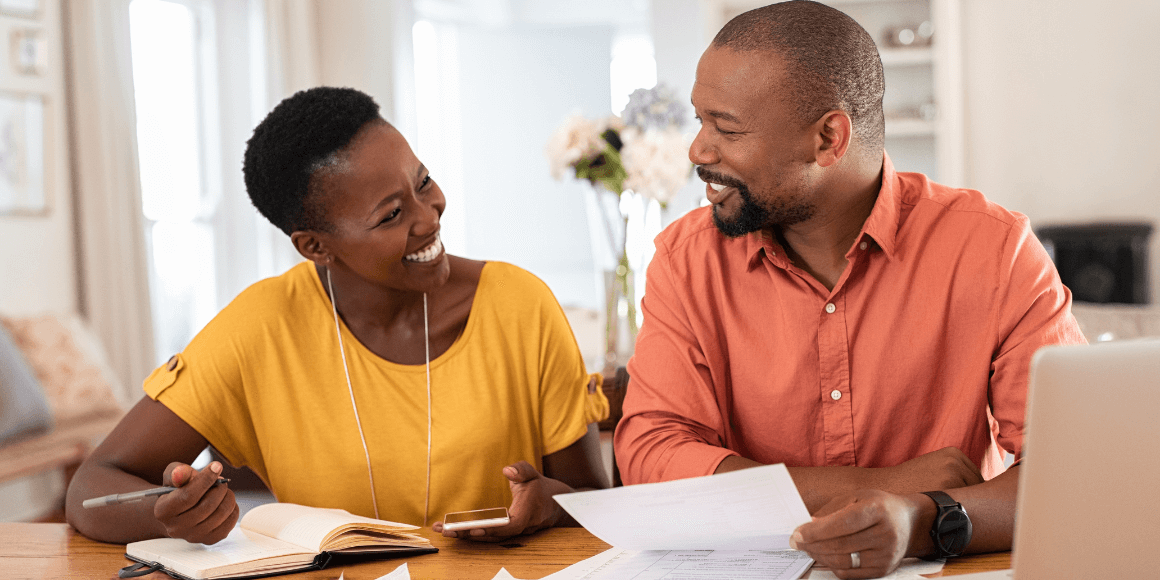 Happy couple sitting at a table reviewing their finances