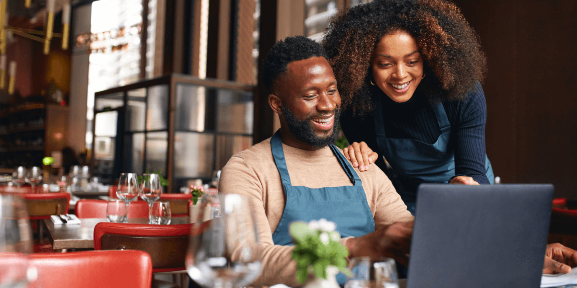 Two small business owners reviewing their finances at a restaurant table