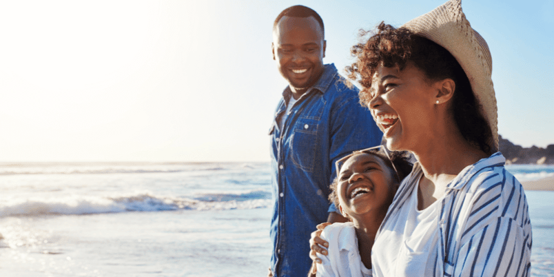 Laughing family walking on a beach because they learned how to budget for a vacation