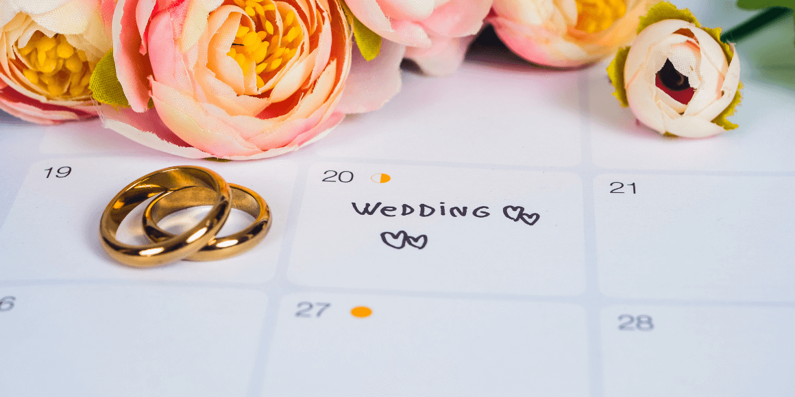 Roses and wedding rings laying on top of a calendar 
