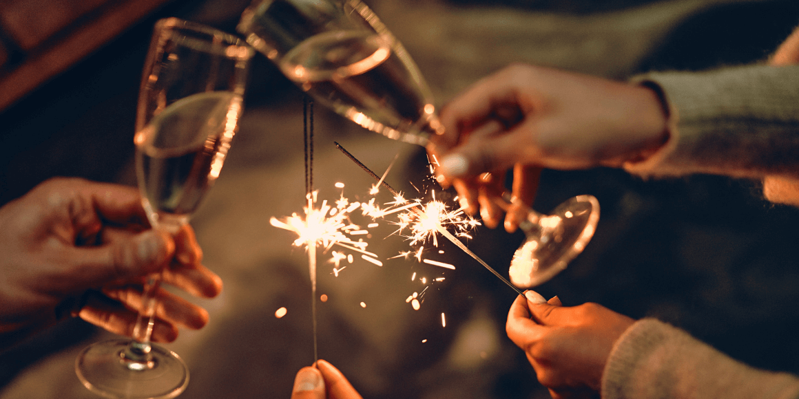 friends toasting champagne an lighting sparklers to celebrate the new year