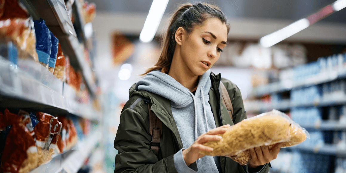 Women checking prices of pasta in a grocery store