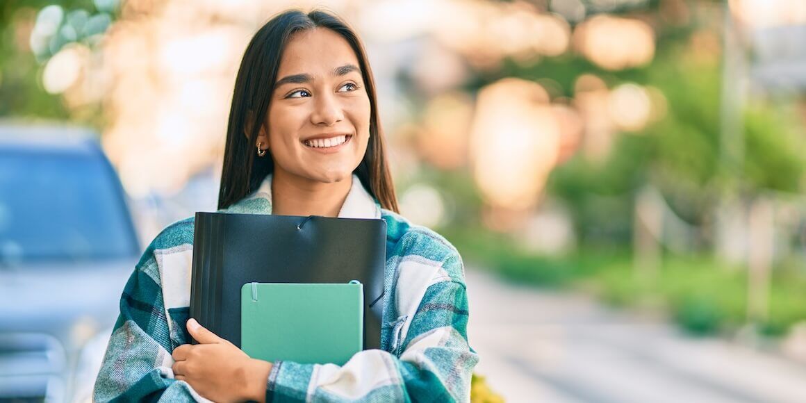 Optimistic student holding a notebook and folder, planning for college savings with financial aid, 529 plans, and scholarship opportunities.