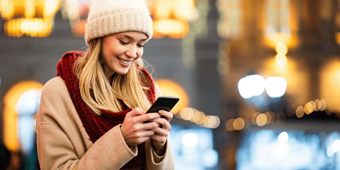 Happy woman using her mobile phone while holiday shopping in the city