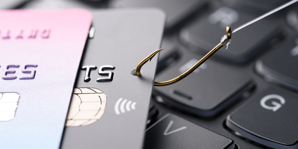 Credit cards attached a to a fishing hook on top of a keyboard 