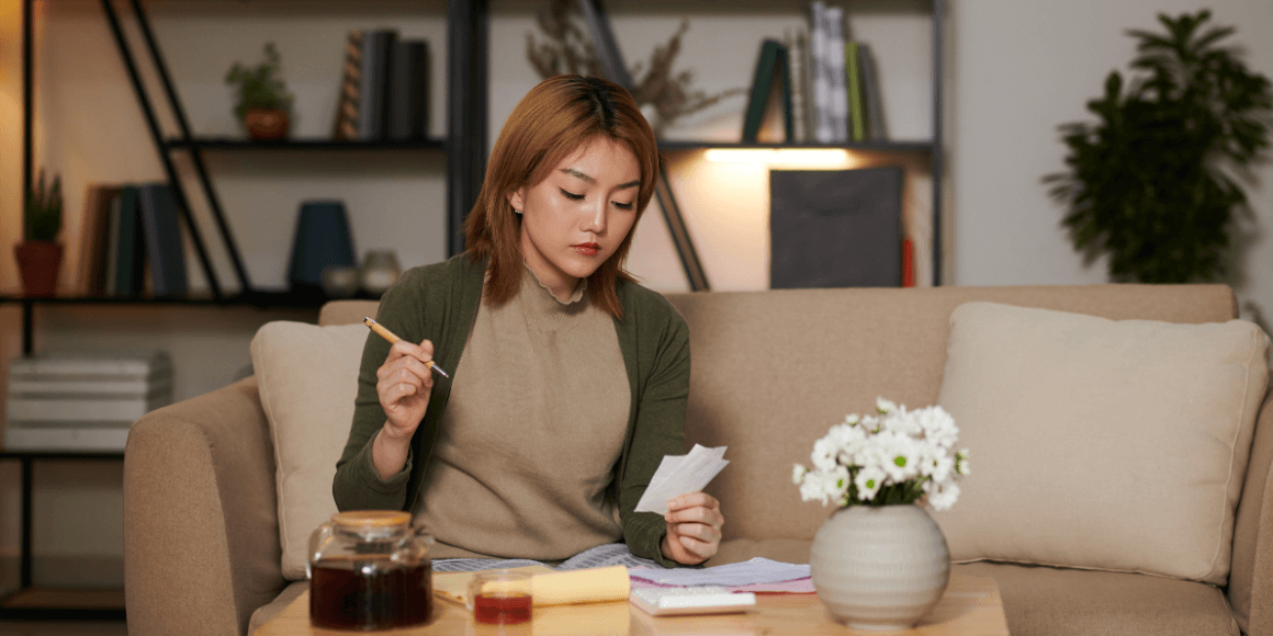 Serious young woman engaged in money management, diligently checking her bills and paychecks for effective financial planning.
