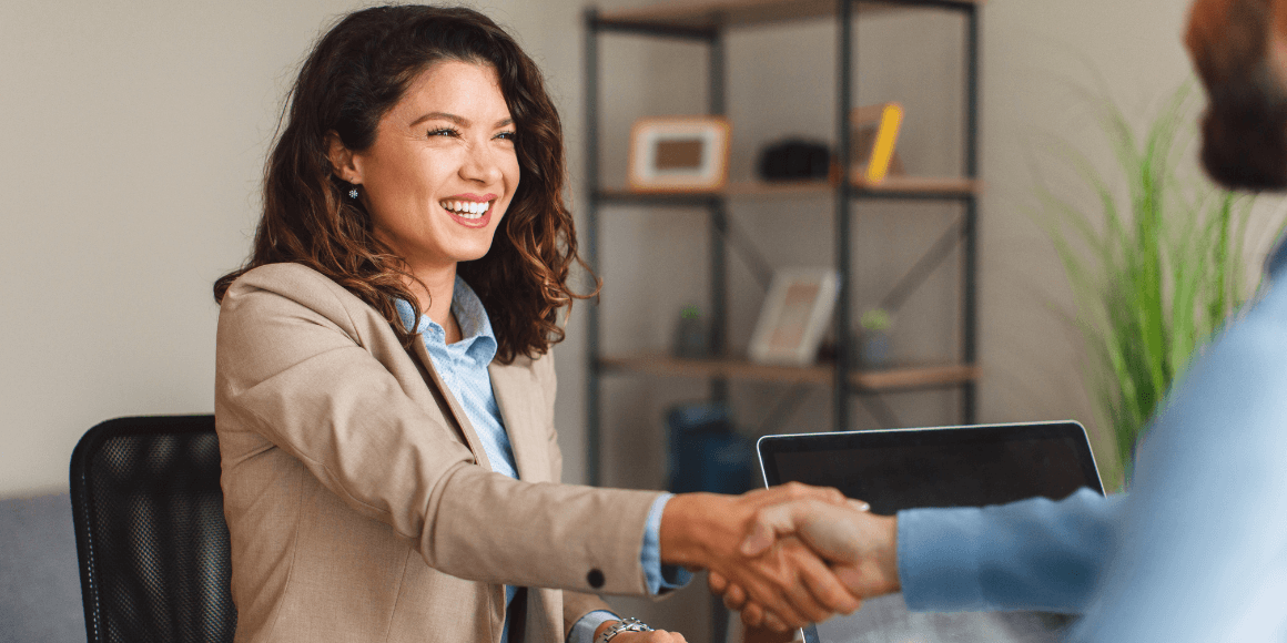 Woman shaking hands with a bank worker after signing for a mortgage for their business.